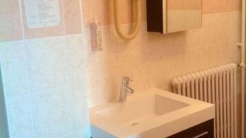 A bathroom with a white sink, a black cabinet, a towel rack, and a radiator.