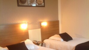 Two single beds with headboards, a bedside table with a lamp, and a framed picture on the wall. - Brit Hotel le Magdalena (Varennes-Vauzelles)