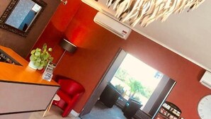 A modern kitchen with a red countertop, a hanging light fixture, and a view of the outdoors. - Brit Hotel le Magdalena (Varennes-Vauzelles)