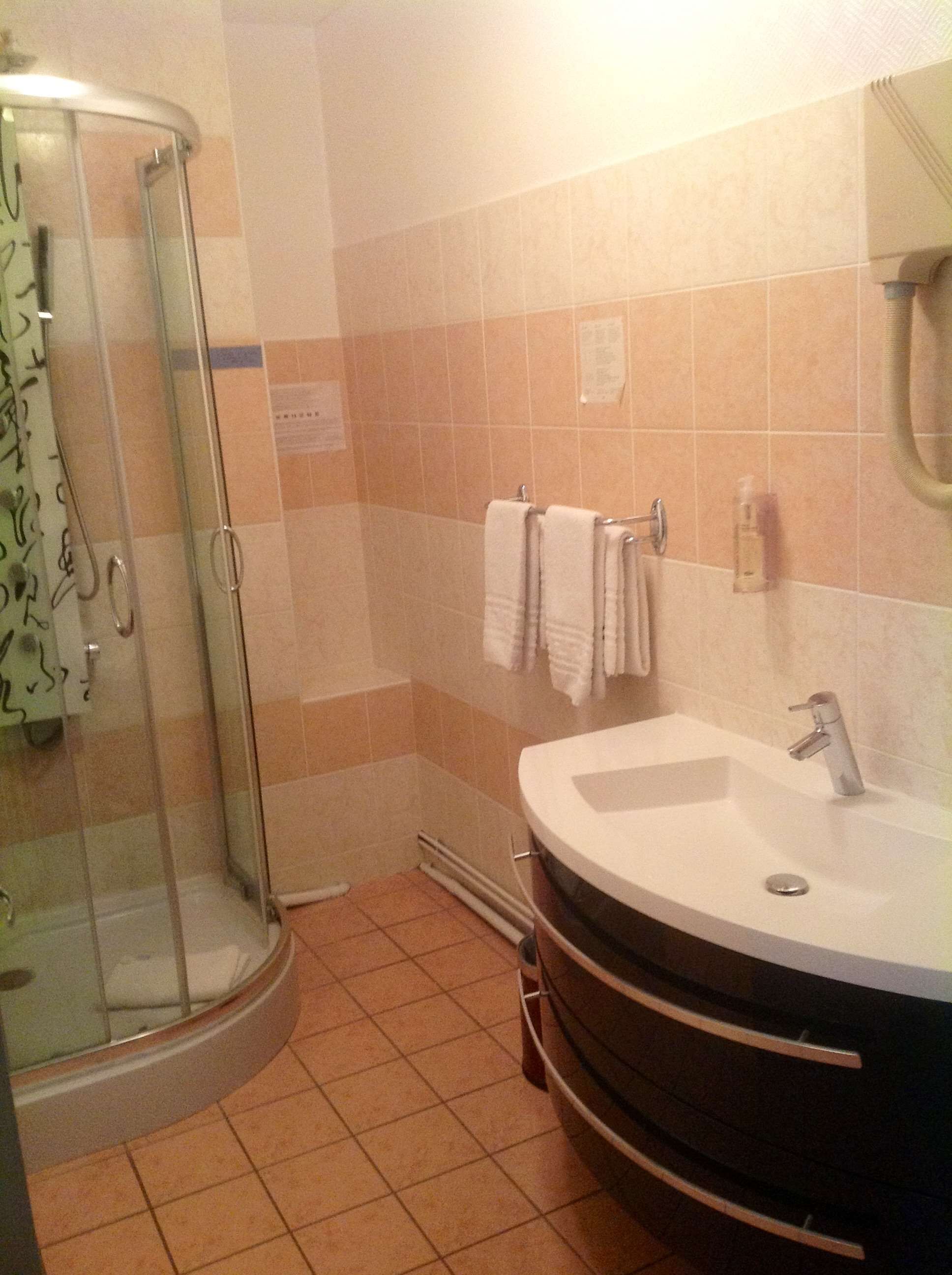 Un baño con ducha envuelta en vidrio, un lavamanos amplio y un espejo.