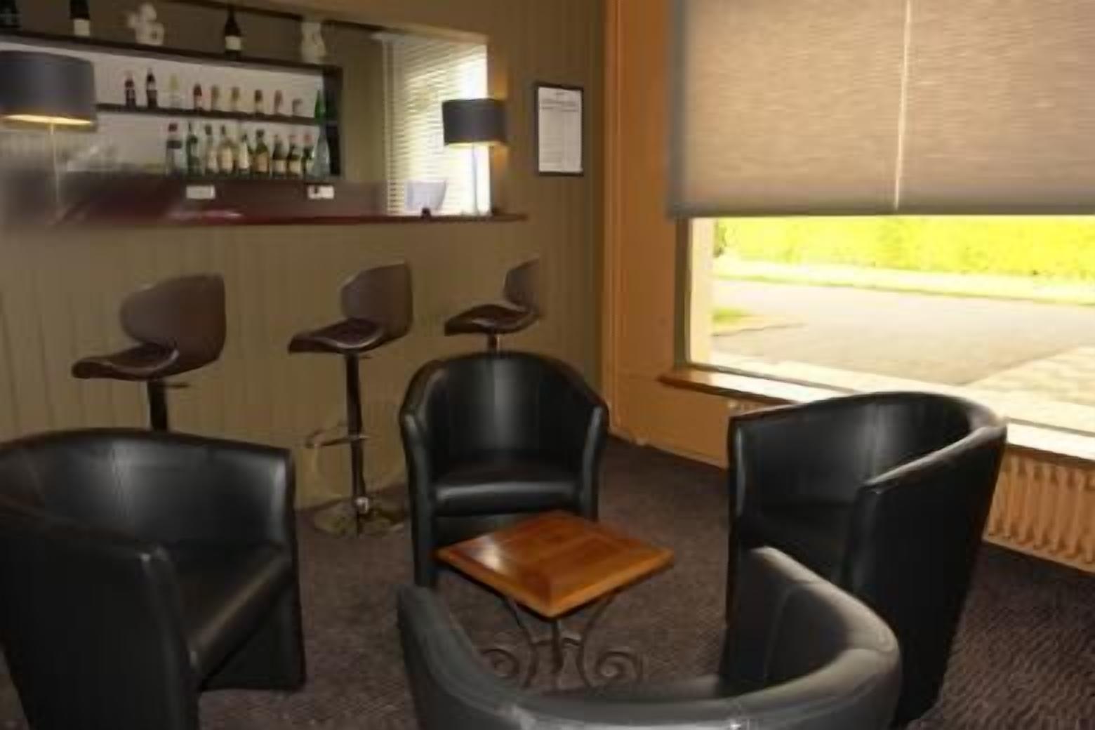 Un espace bar avec un comptoir et plusieurs chaises.