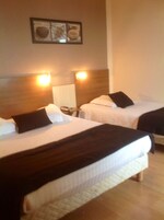 Habitación de hotel con dos camas, cada una con cabecera y lámparas de noche.