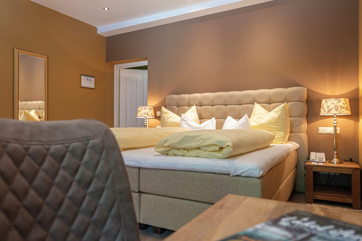 A hotel room with a bed, bedside lamps, a chair, and a small table.