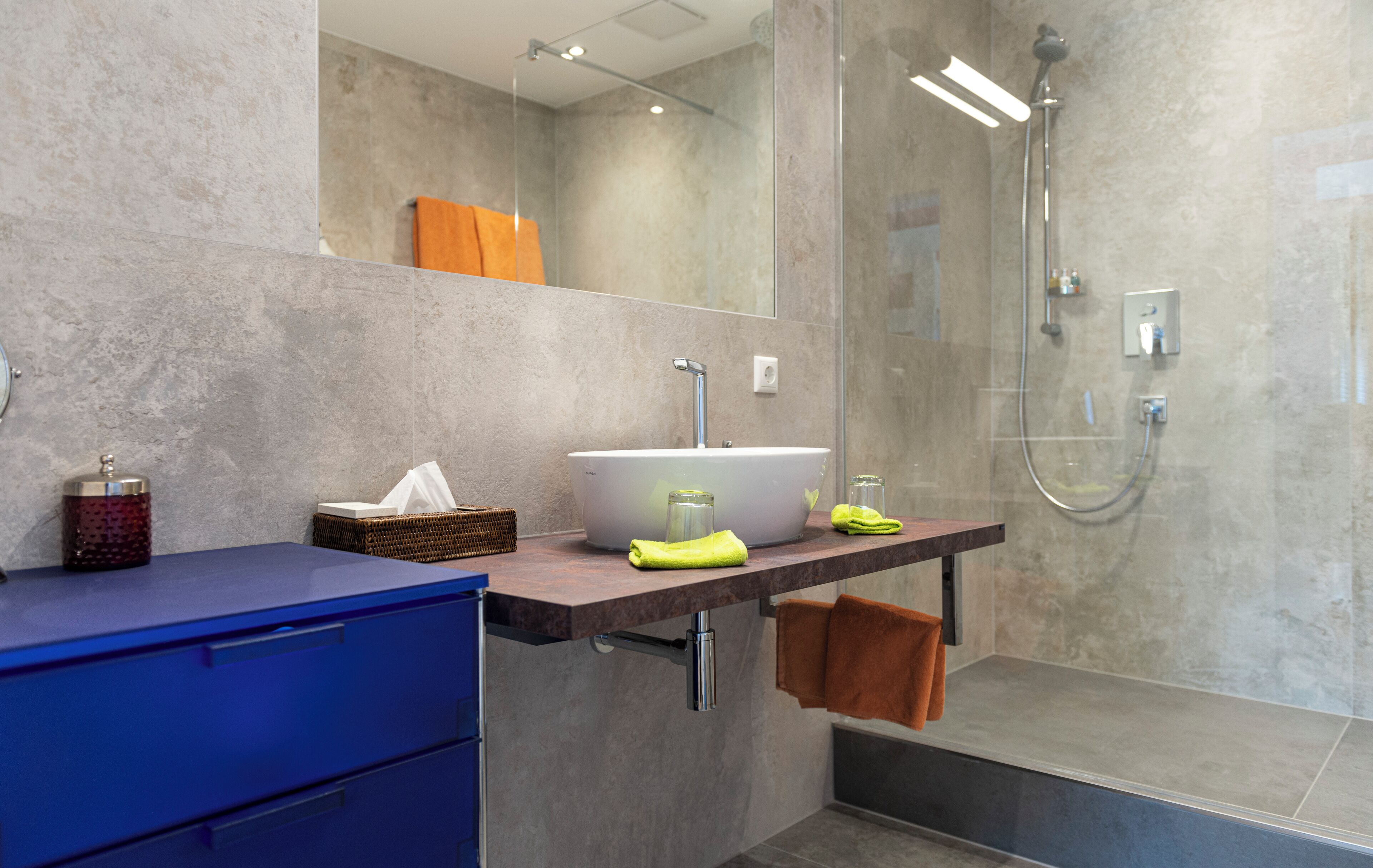 A modern bathroom with a large mirror, a sink, and a shower.