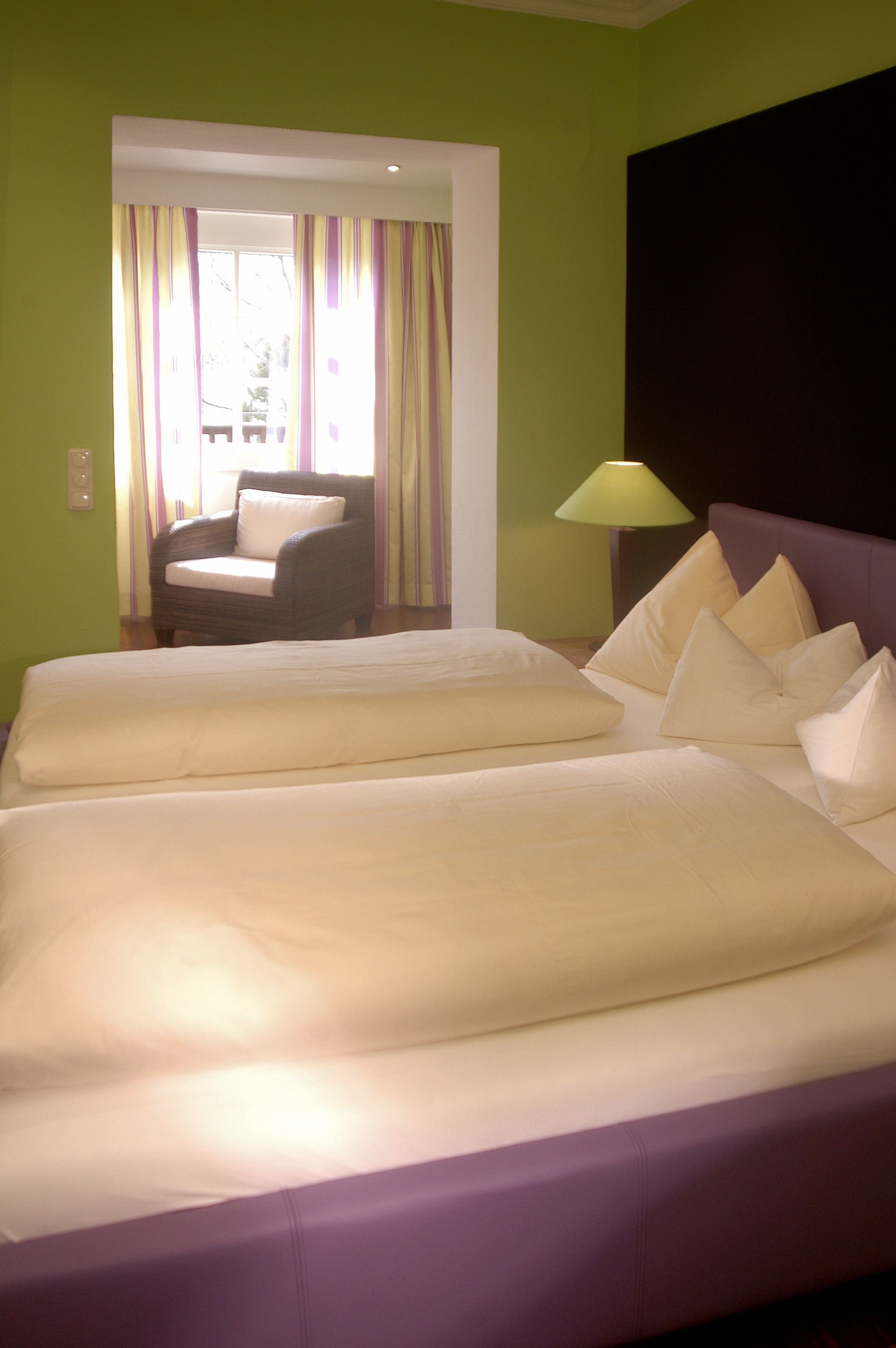 Una habitación de hotel con una cama grande, una silla y una lámpara.