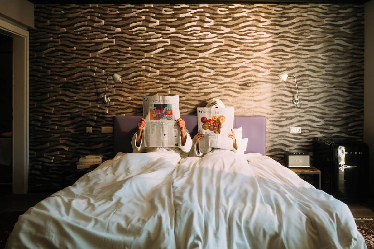 A bed with a patterned headboard, a bedside table with a lamp, and a water dispenser.