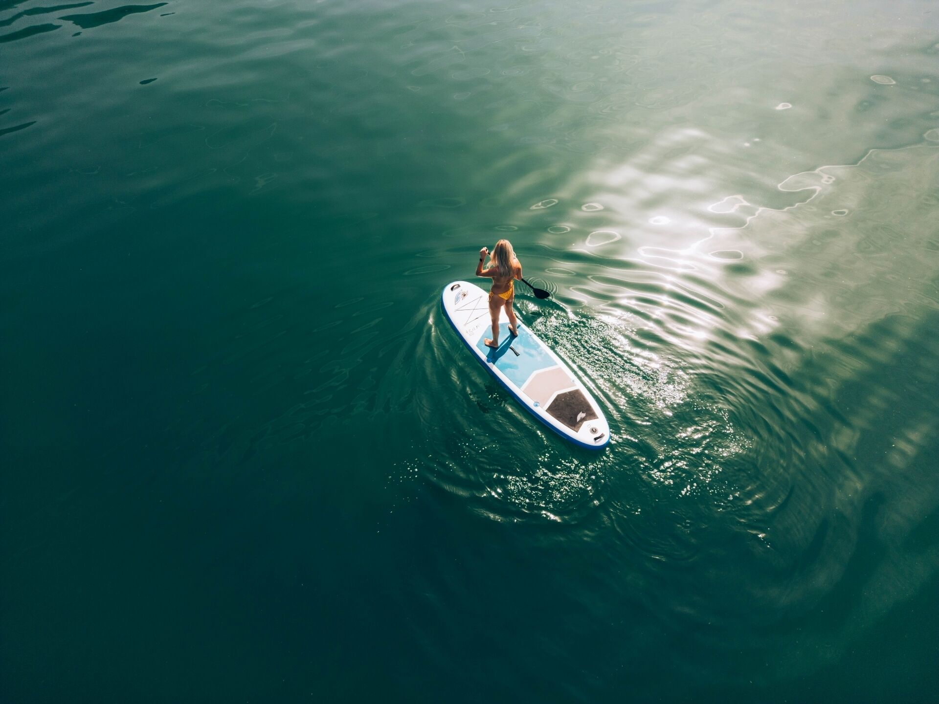 A person standing on a paddleboard in calm water.