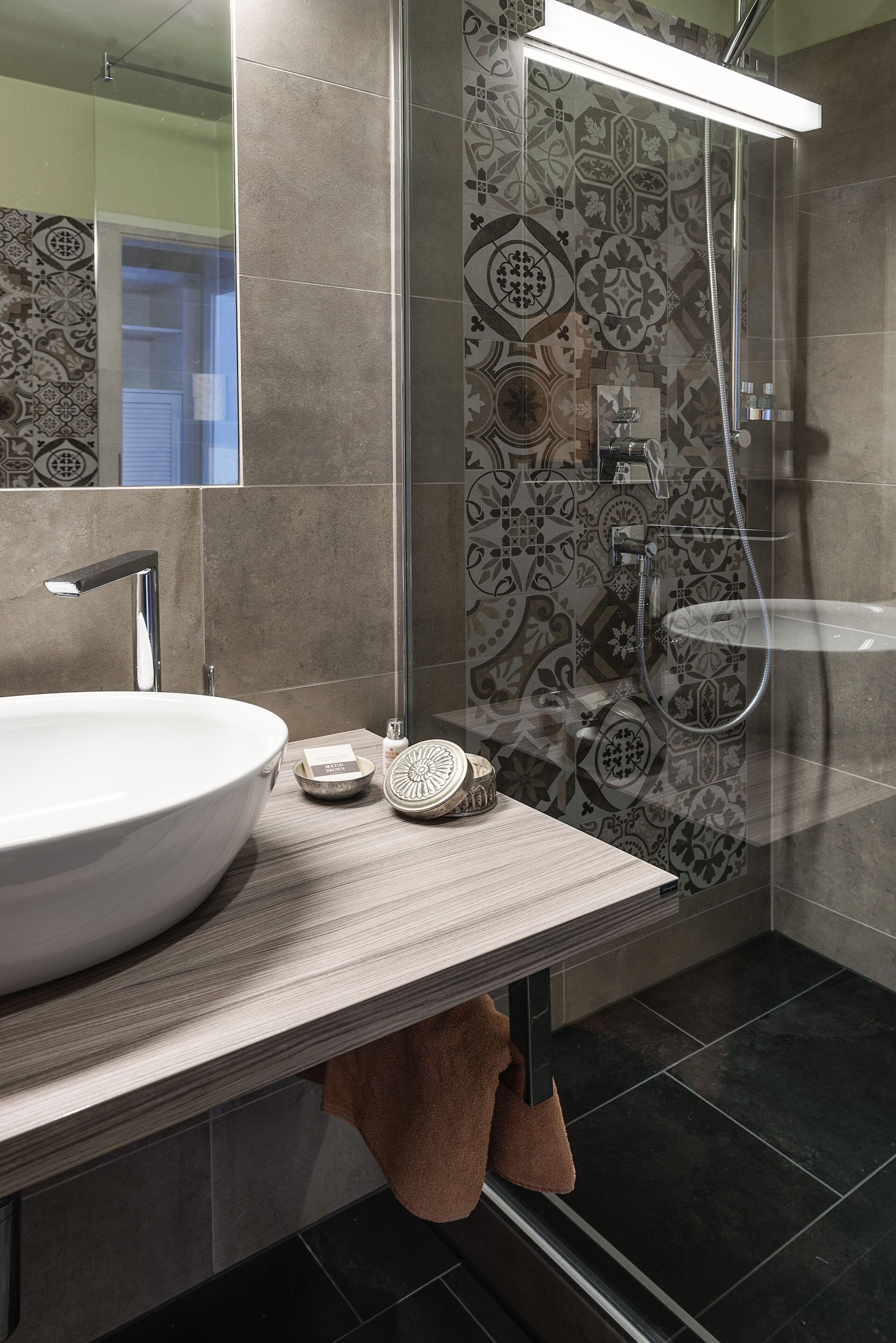 A modern bathroom with a large white sink, a mirror, and a shower area.