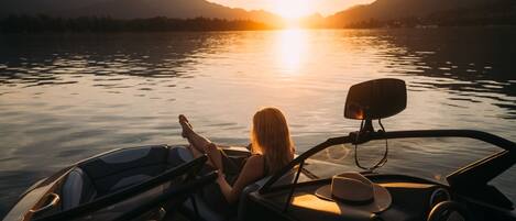 Una persona descansando en un barco con un atardecer de fondo.
