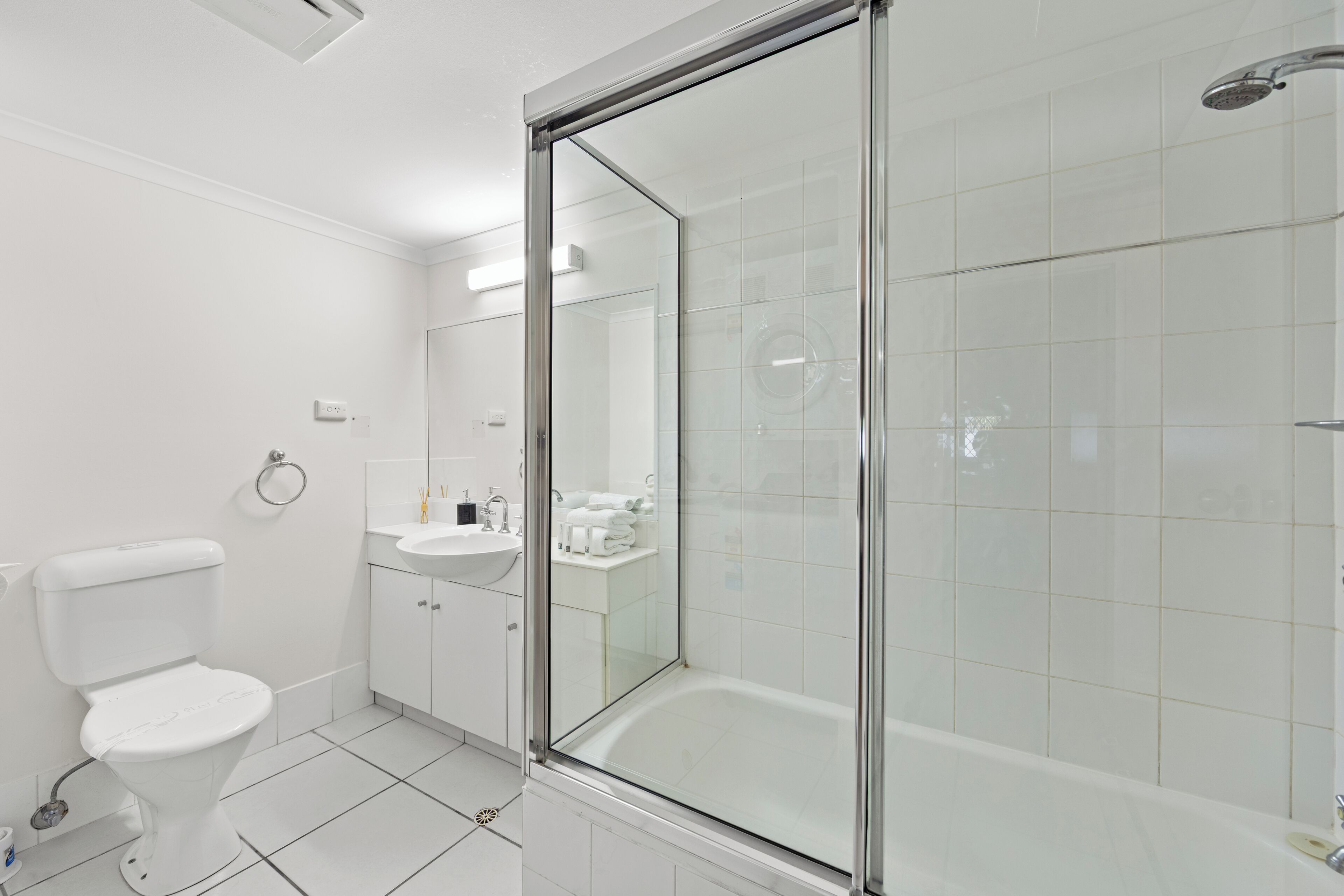 A modern bathroom with a toilet, sink, and glass-enclosed shower.