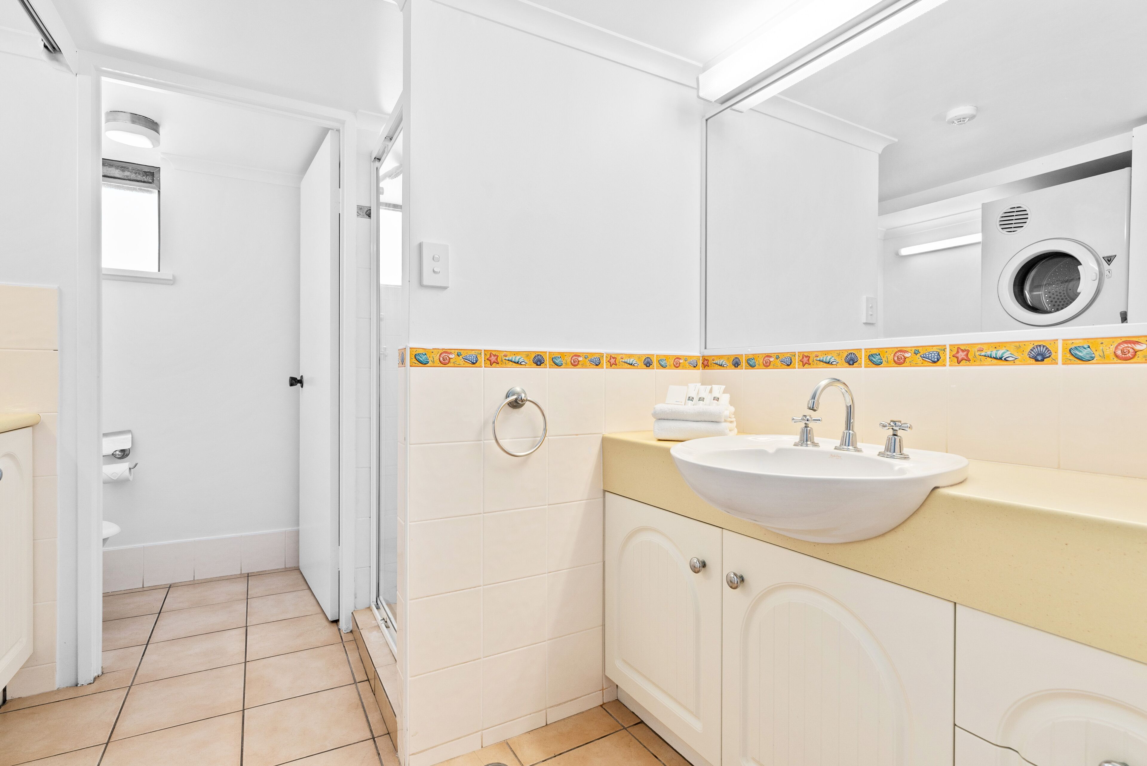A bathroom with a sink, mirror, and a washing machine.