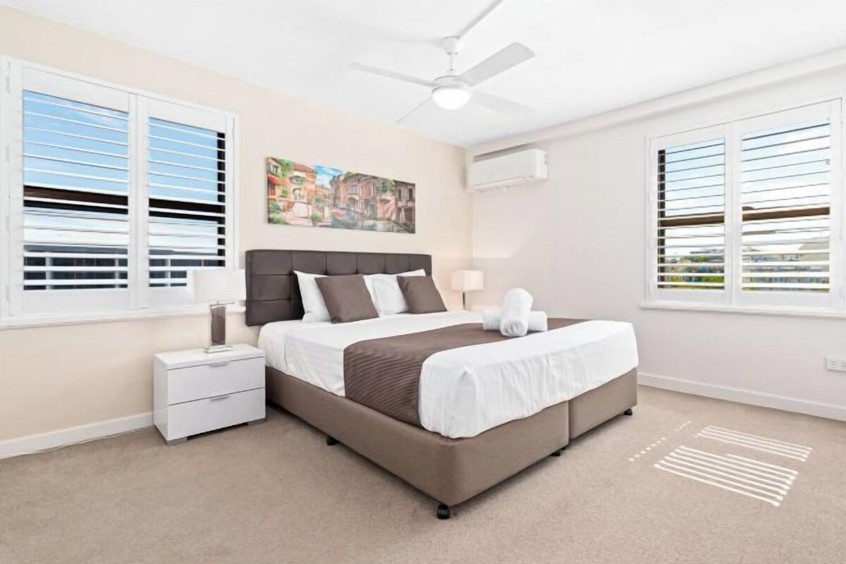 A bedroom with a bed, nightstand, lamp, and a ceiling fan.
