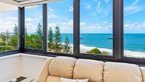 Quarto com uma janela grande com vista para uma praia e oceano.