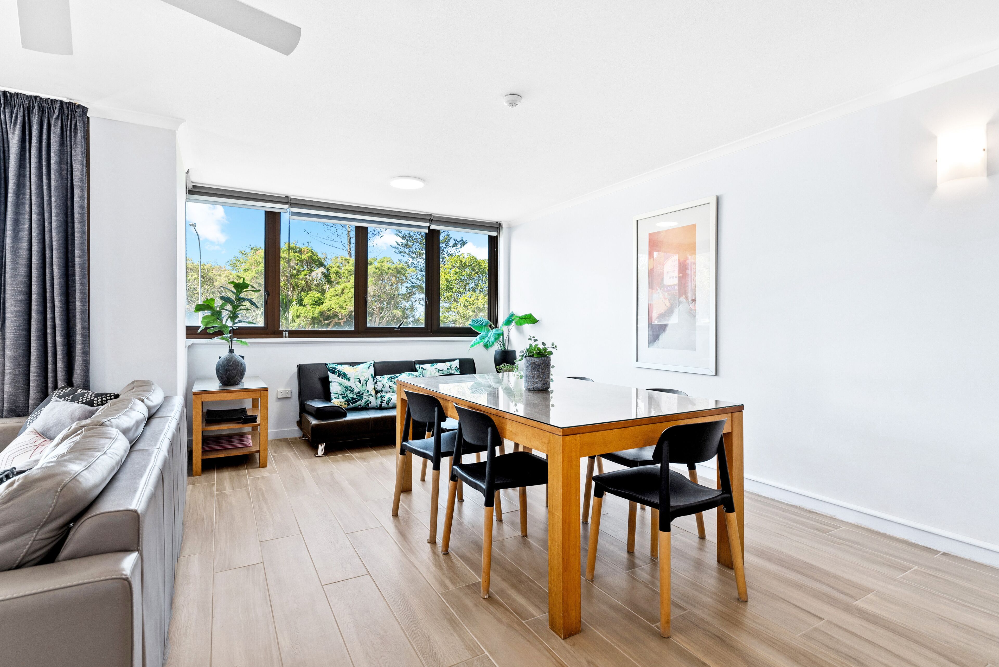 Una sala de estar moderna con comedor, ventanas amplias, un sofá y una mesa de centro.