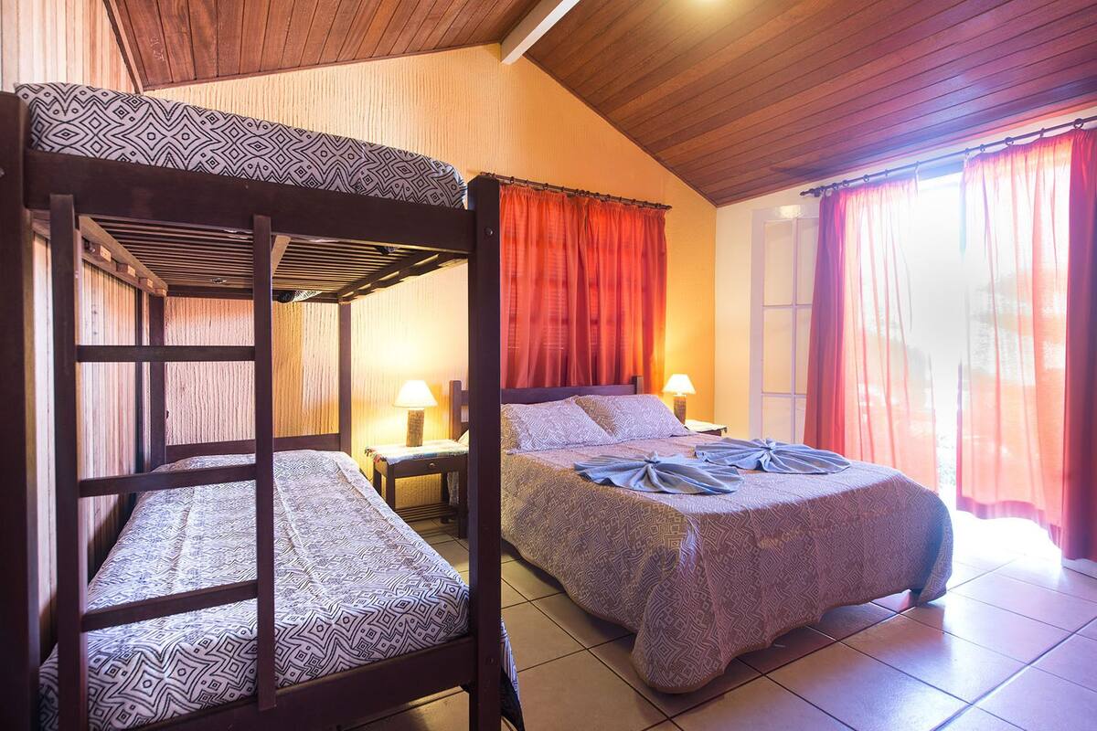 Quarto com uma cama de solteiro, uma cama individual e uma mesa de cabeceira com luminária.