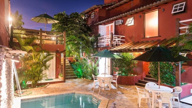 A pool area with a hot tub, outdoor seating, and a staircase leading to a balcony. - Meu Sonho Pousada (Búzios)