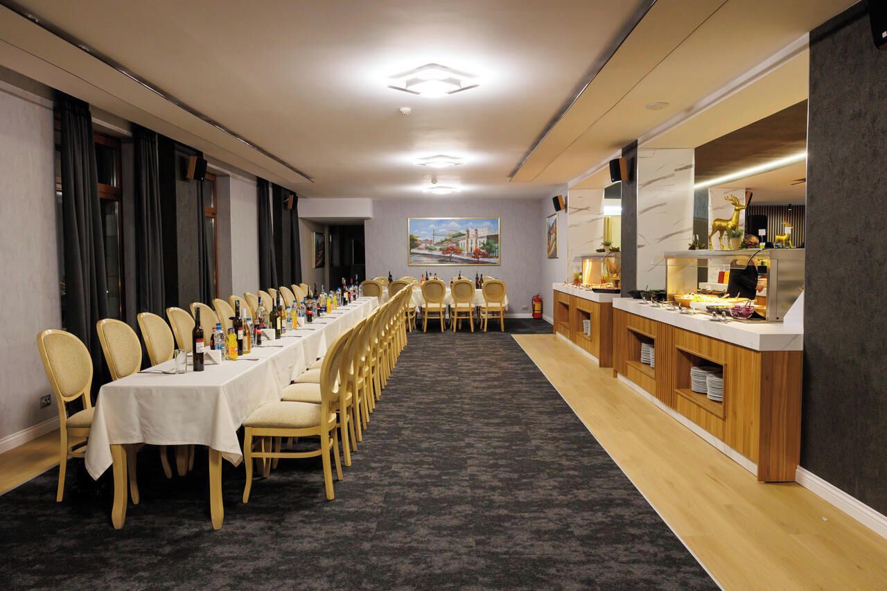 A conference room with a long table, chairs, and a buffet area.