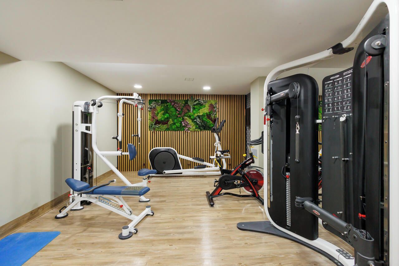 A gym with exercise equipment including a treadmill, elliptical, and weight machines.