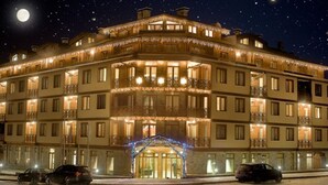 A multi-story hotel with balconies, a central entrance, and a starry night sky. - Vihren Palace Ski & Spa Resort (Bansko)