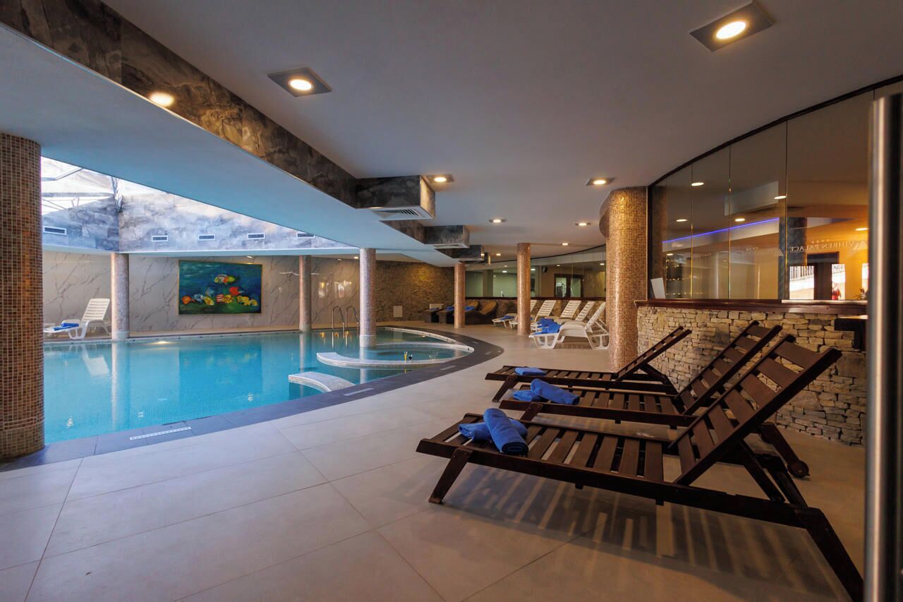 An indoor swimming pool with lounge chairs and a mural on the wall.