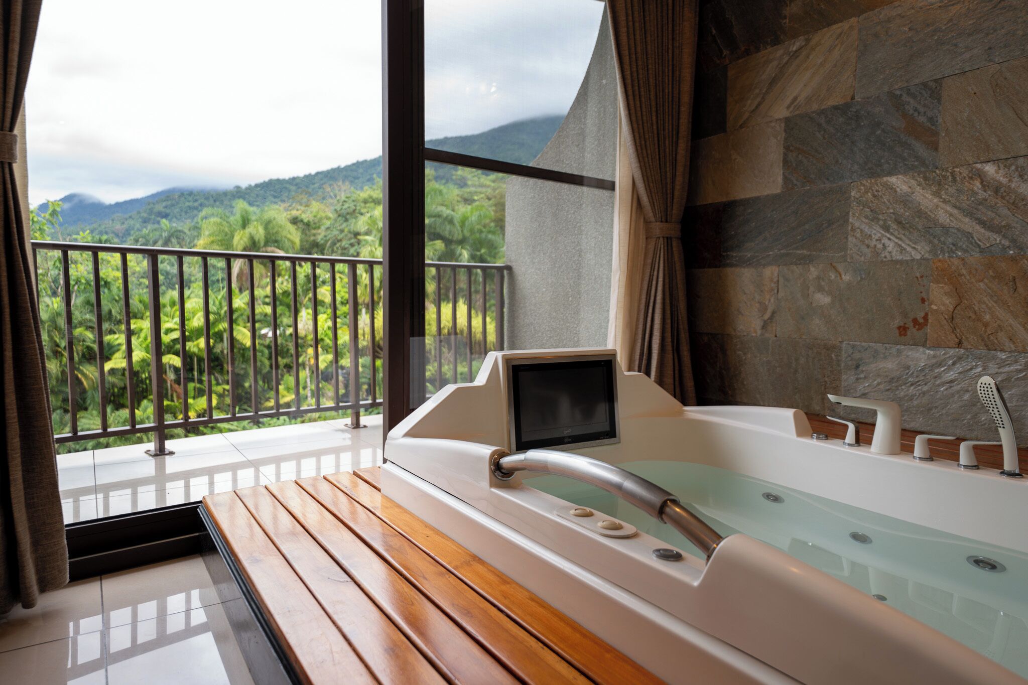 A spa area with a massage chair, a bathtub, and a view of a lush garden and mountains.