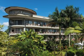 Un hotel de varios pisos con balcones y exuberante jardinería tropical.