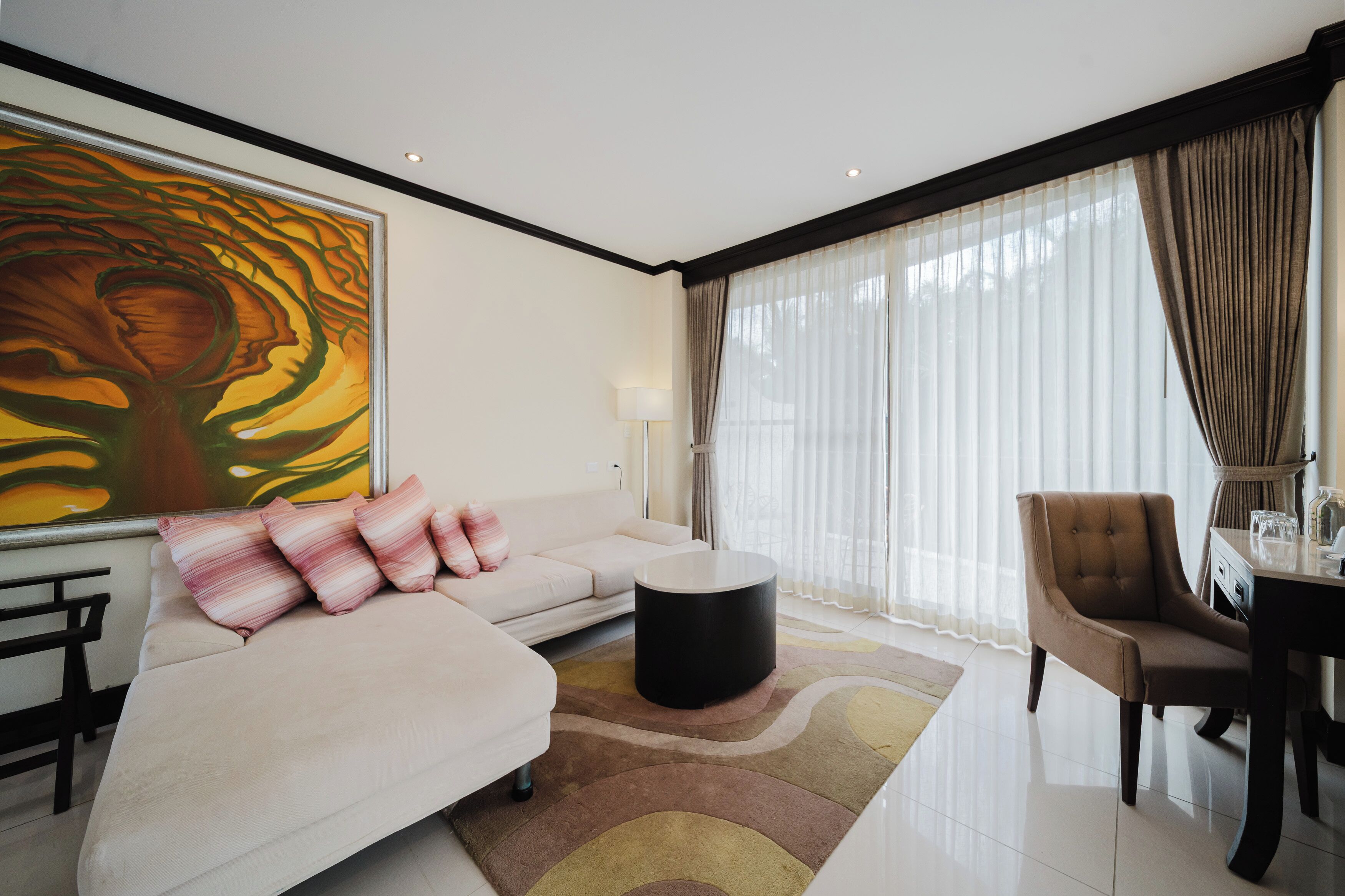 Una sala de estar moderna con sofá, sillón, mesa redonda de centro y un cuadro abstracto grande en la pared.