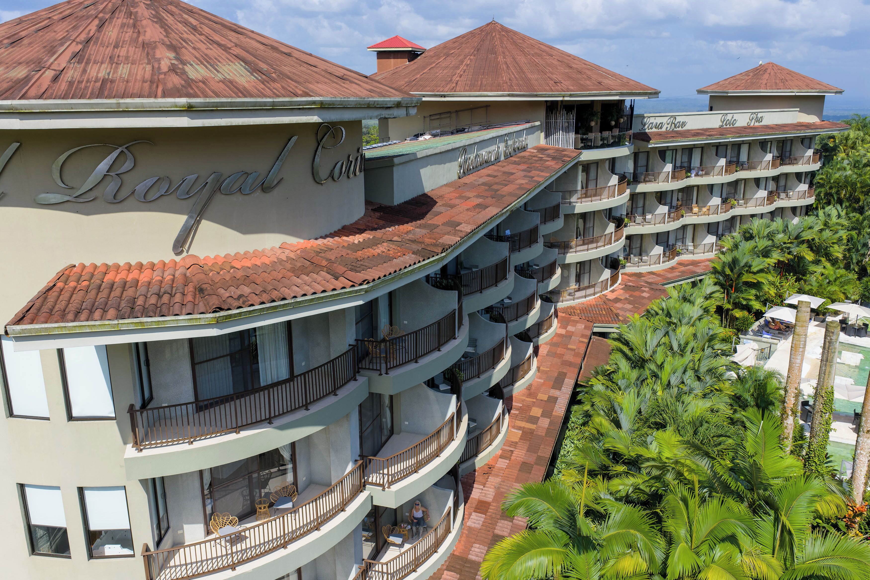 A multi-story hotel with balconies, a swimming pool, and a view of the ocean.