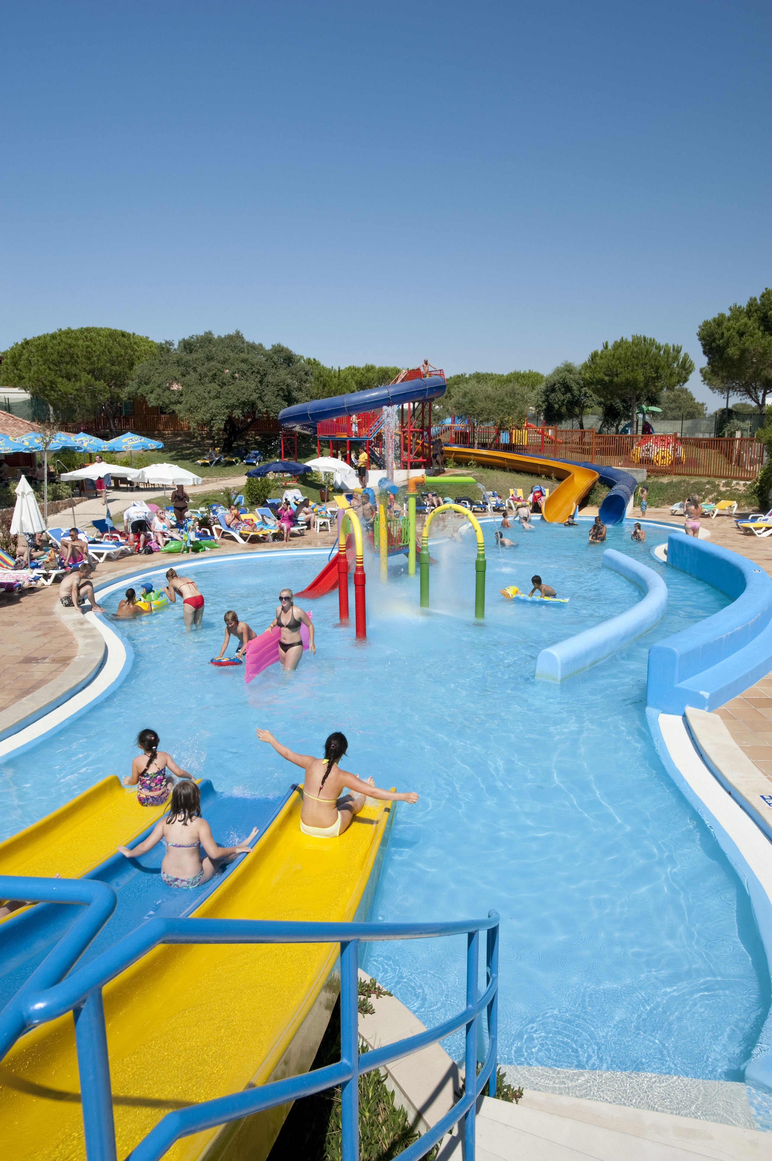 A water park with multiple slides and pools, surrounded by lounge chairs and umbrellas.