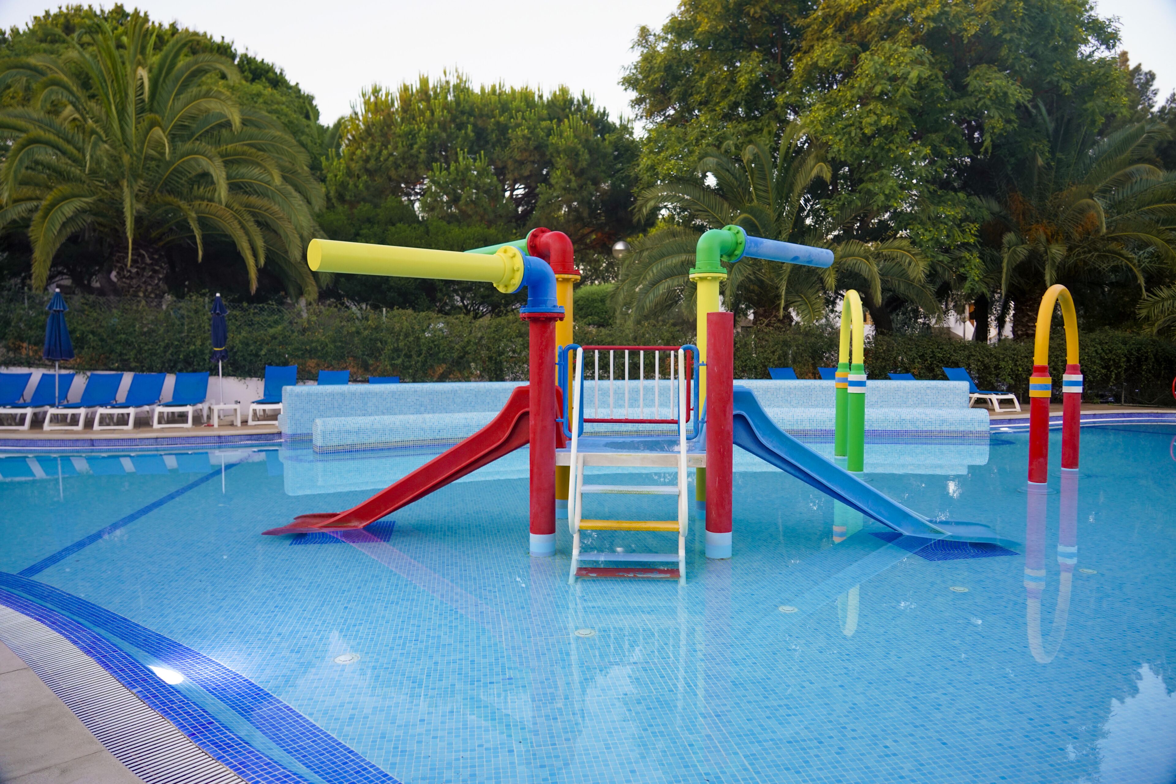 A swimming pool with colorful slides and a ladder.