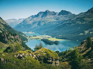 A mountainous landscape with a lake, forested hills, and a small settlement. - Schweizerhof Sils Maria, a Faern Collection Hotel (Sils im Engadin-Segl)