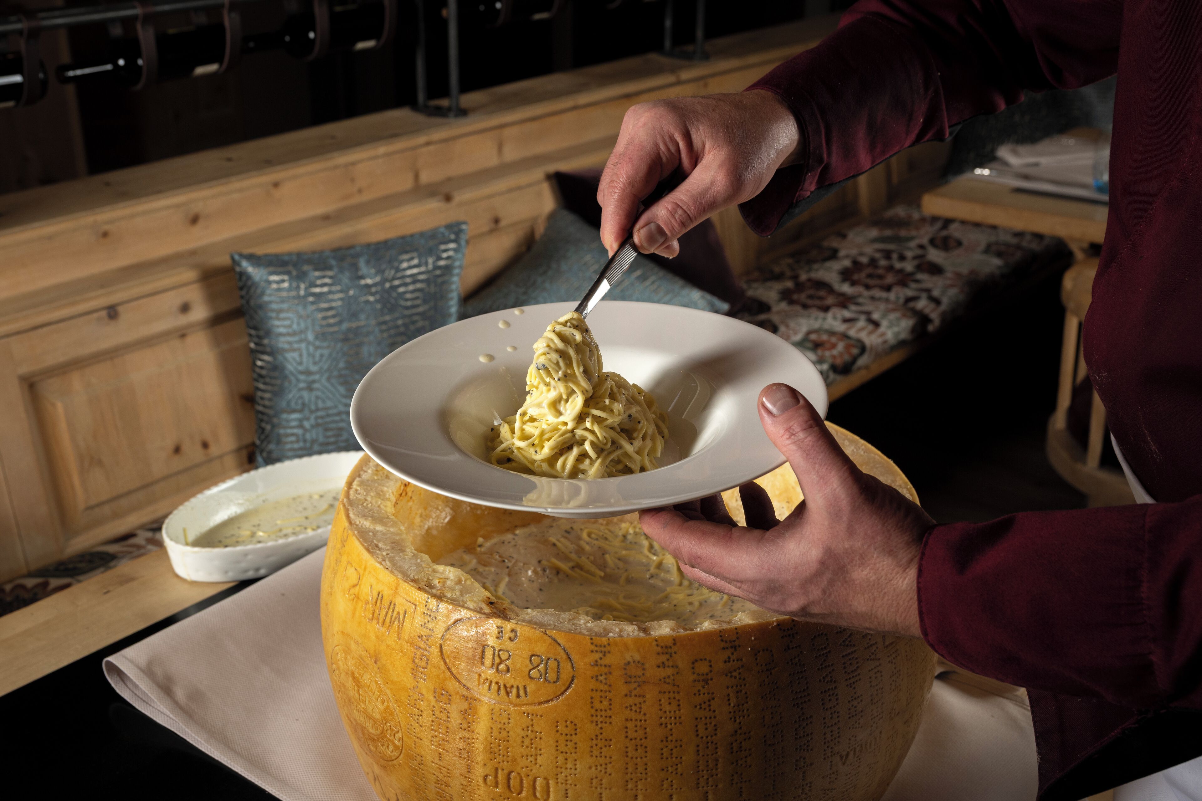 Une personne servant des spaghettis dans une grande meule de fromage.