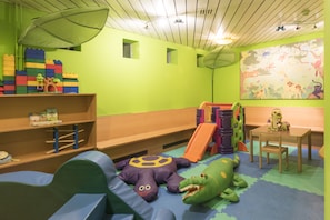 A children's playroom with a slide, soft play mats, and colorful toys. - Schweizerhof Sils Maria, a Faern Collection Hotel (Sils im Engadin-Segl)