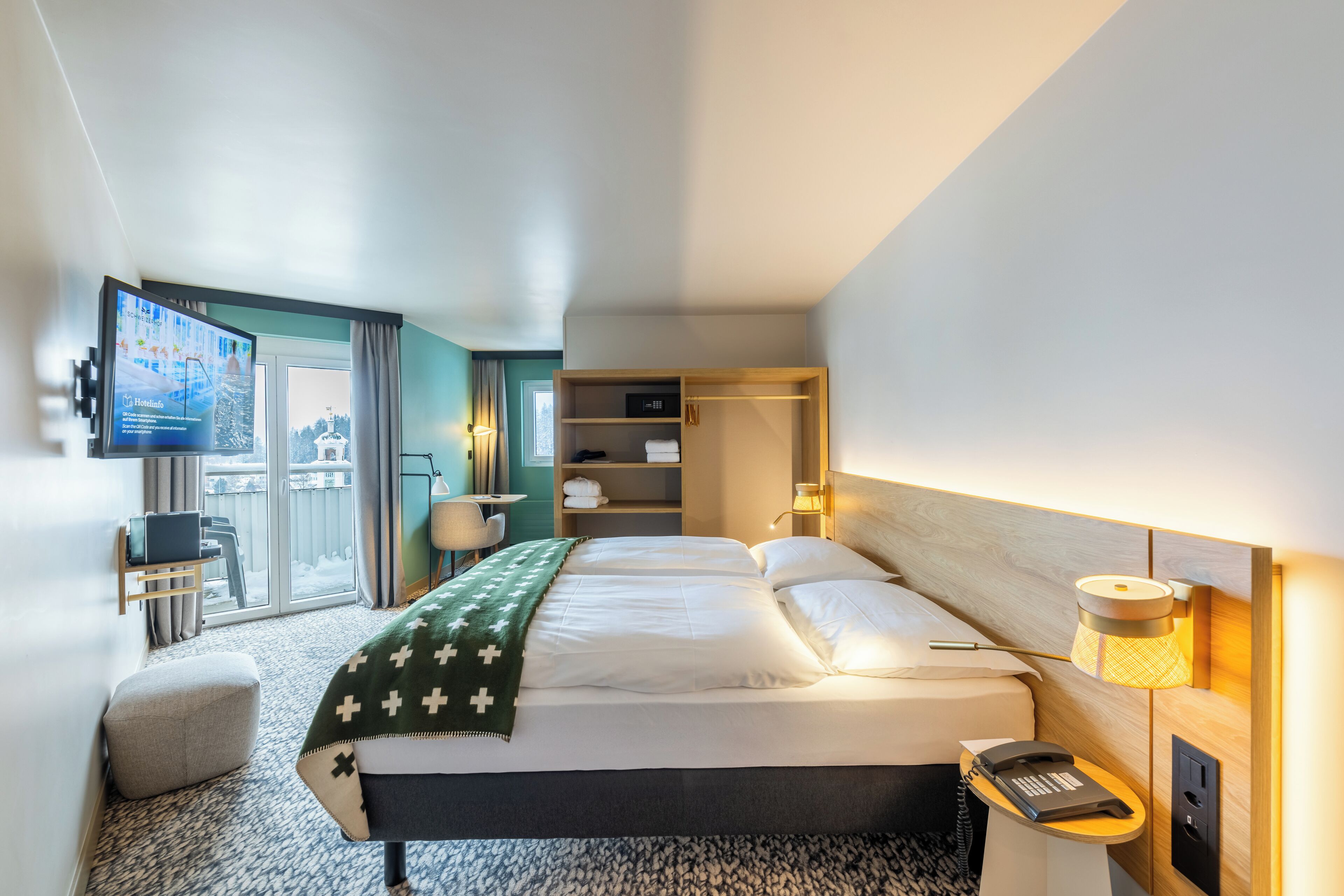 Une chambre d’hôtel moderne équipée d’un lit, d’un bureau, d’une télévision et offrant une vue sur l’extérieur.
