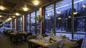 A restaurant with tables set for dining, large windows offering a view of a snowy landscape. - Schweizerhof Sils Maria, a Faern Collection Hotel (Sils im Engadin-Segl)