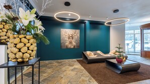 A modern interior with a stone-tiled floor, a dark blue accent wall, and a large window offering a view. - Schweizerhof Sils Maria, a Faern Collection Hotel (Sils im Engadin-Segl)