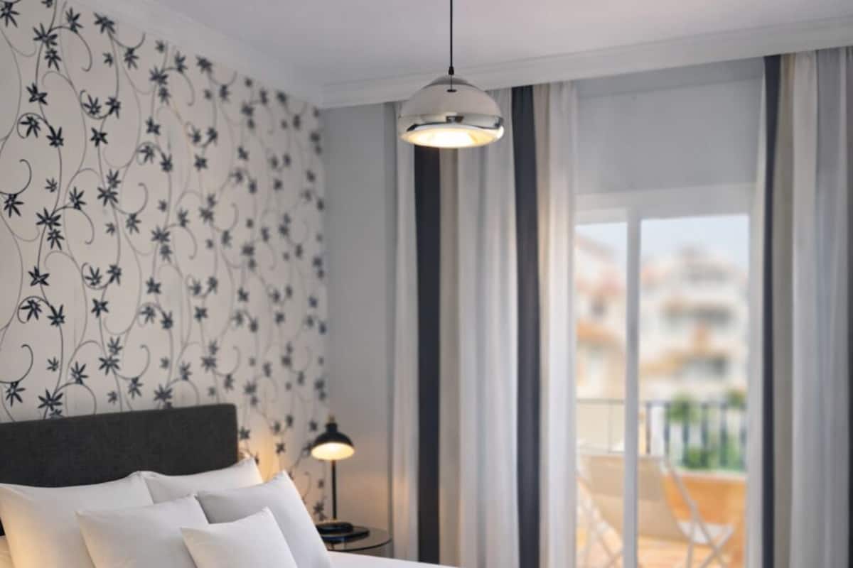 Un dormitorio moderno con una cama grande, una lámpara colgante y vistas al exterior.
