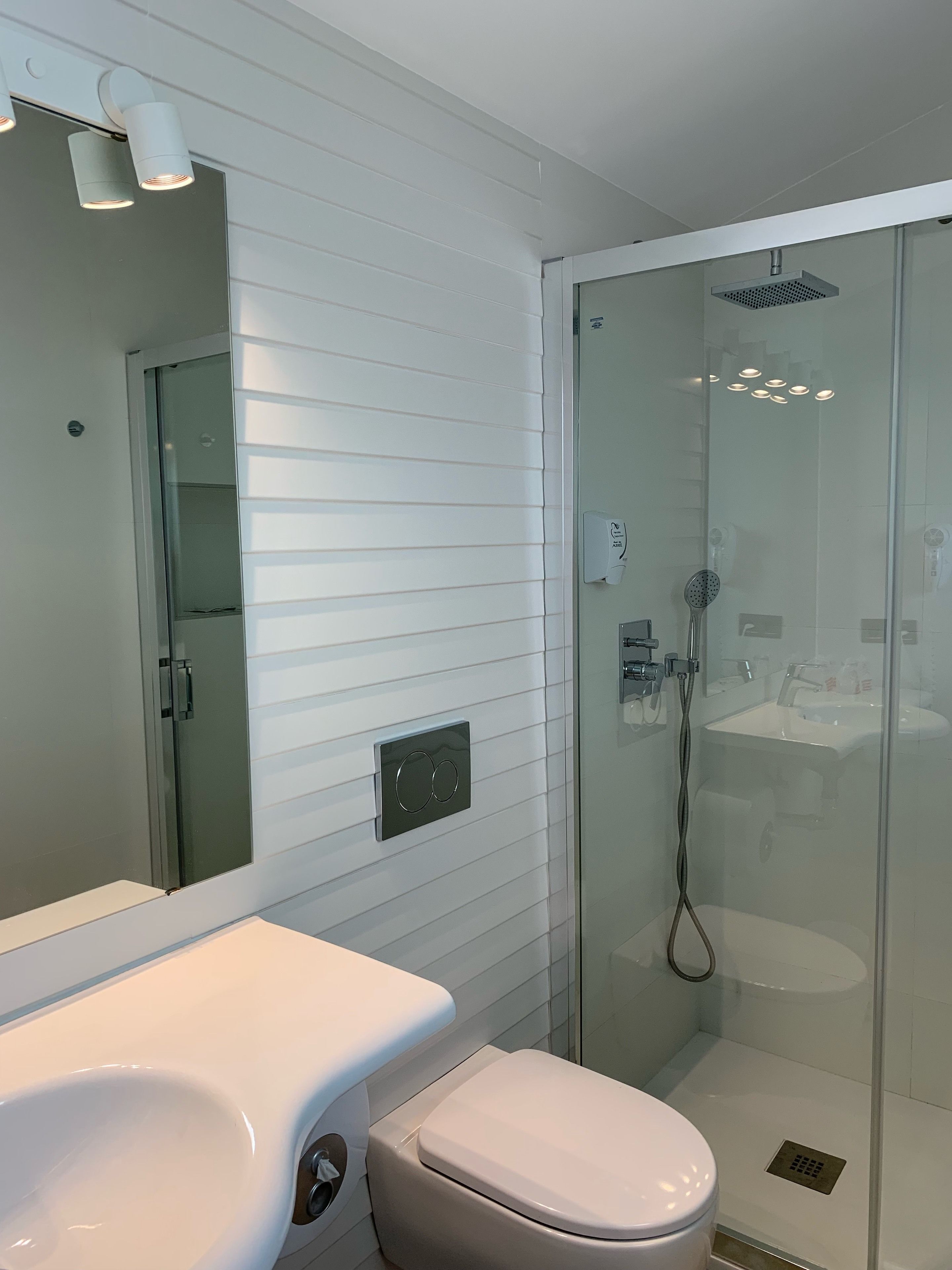 A modern bathroom with a glass-enclosed shower, a white sink, and a toilet.