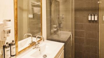 A bathroom with a white sink, a mirror, and a shower area with a tiled wall.