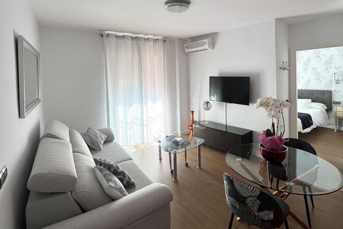 Una sala de estar moderna con un sofá, una mesa de centro de vidrio y un televisor.