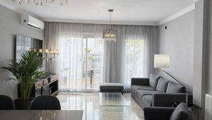 A modern living room with a sofa, a glass coffee table, a TV, and a chandelier. - Abril Nerja (Nerja)