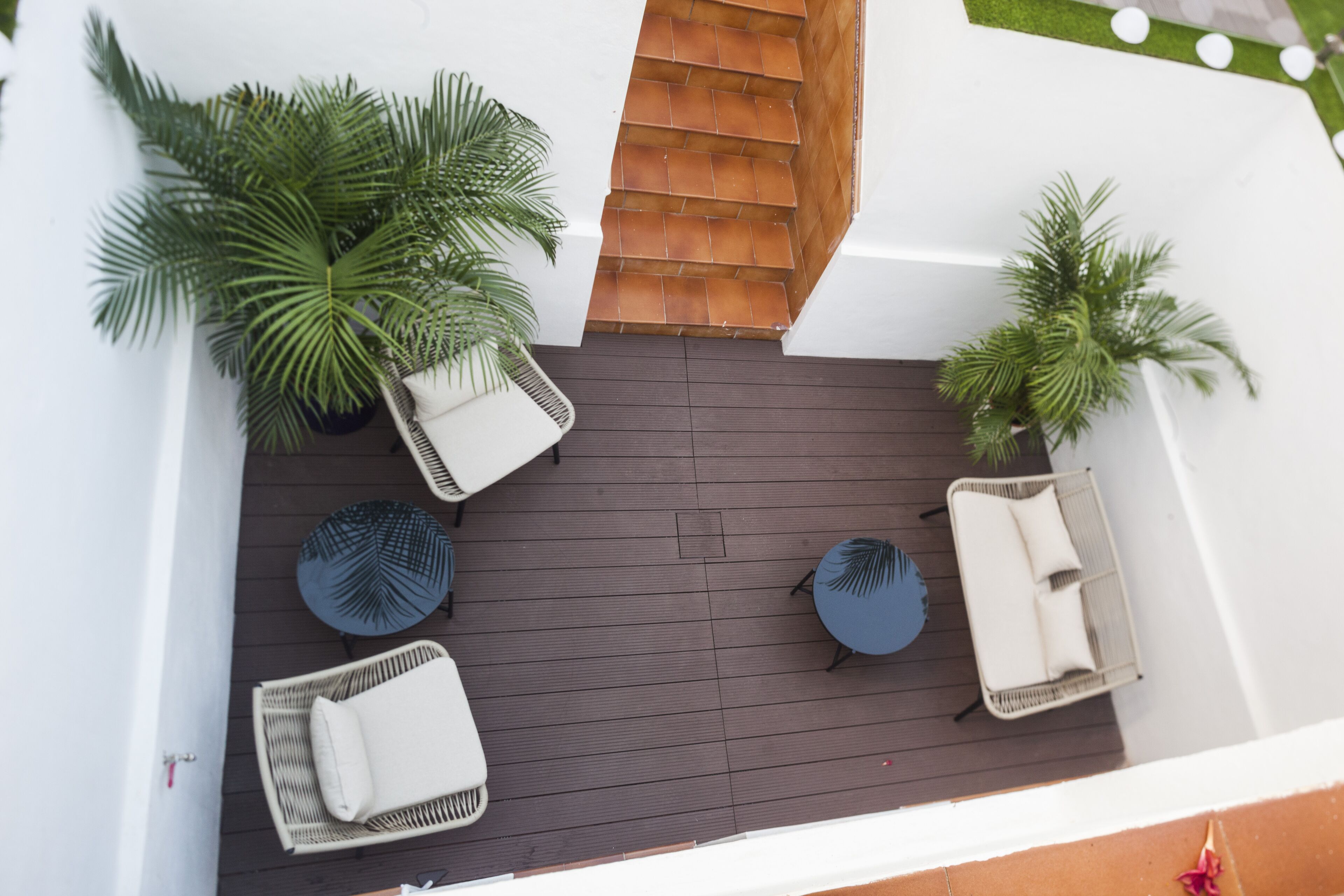 A rooftop patio with wicker chairs, a small round table, and potted plants.