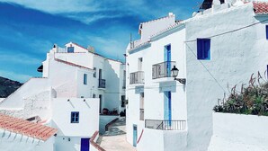 A white building with blue doors and windows, a tiled roof, and a clear blue sky. - Abril Nerja (Nerja)