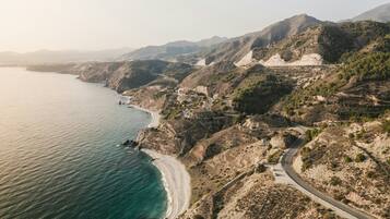 Una carretera costera con playa y terreno montañoso.