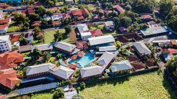 An aerial view of a residential area with houses, a swimming pool, and solar panels.