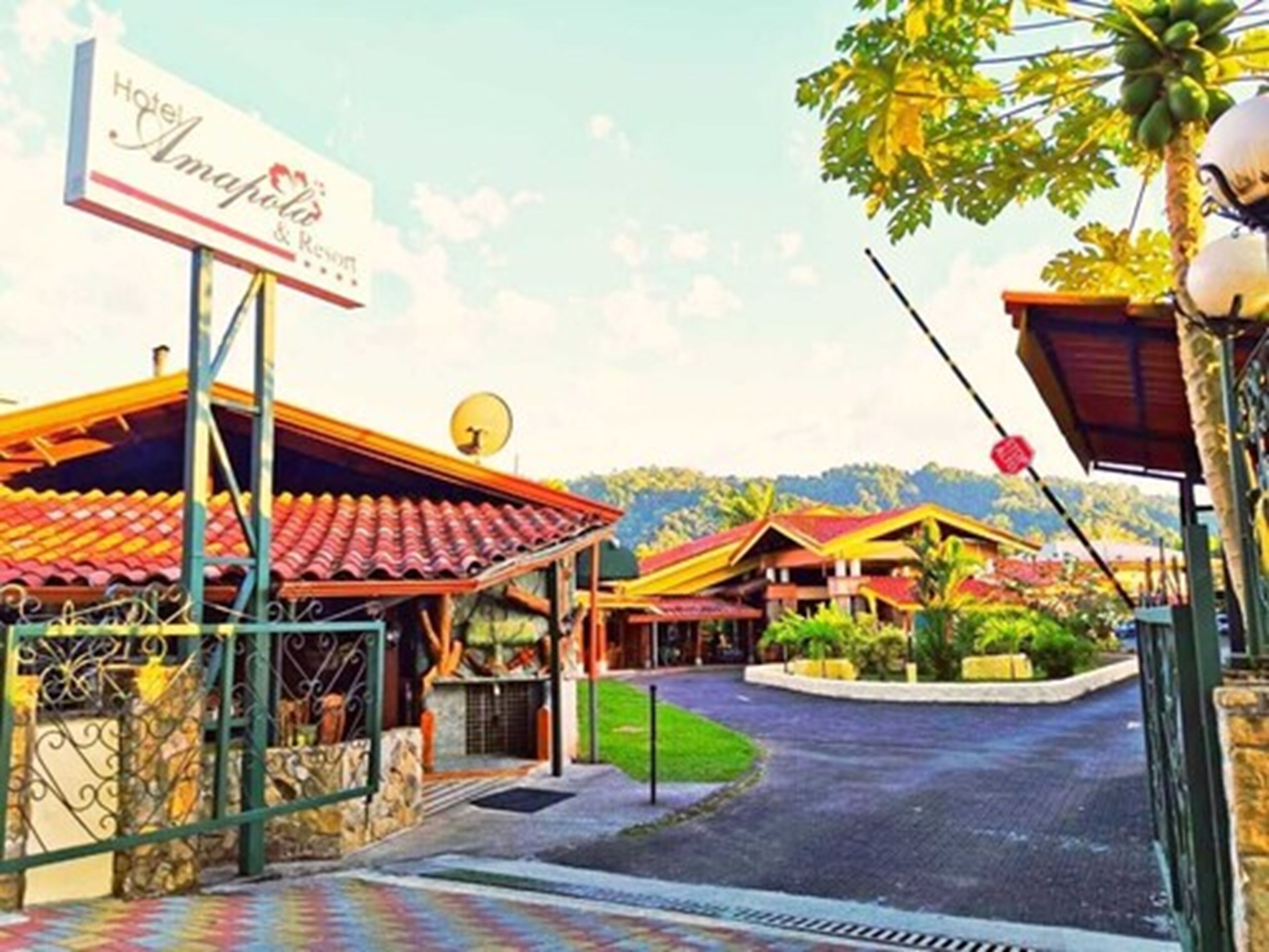 A hotel with a red-tiled roof, a signboard, and a pathway leading to the entrance.