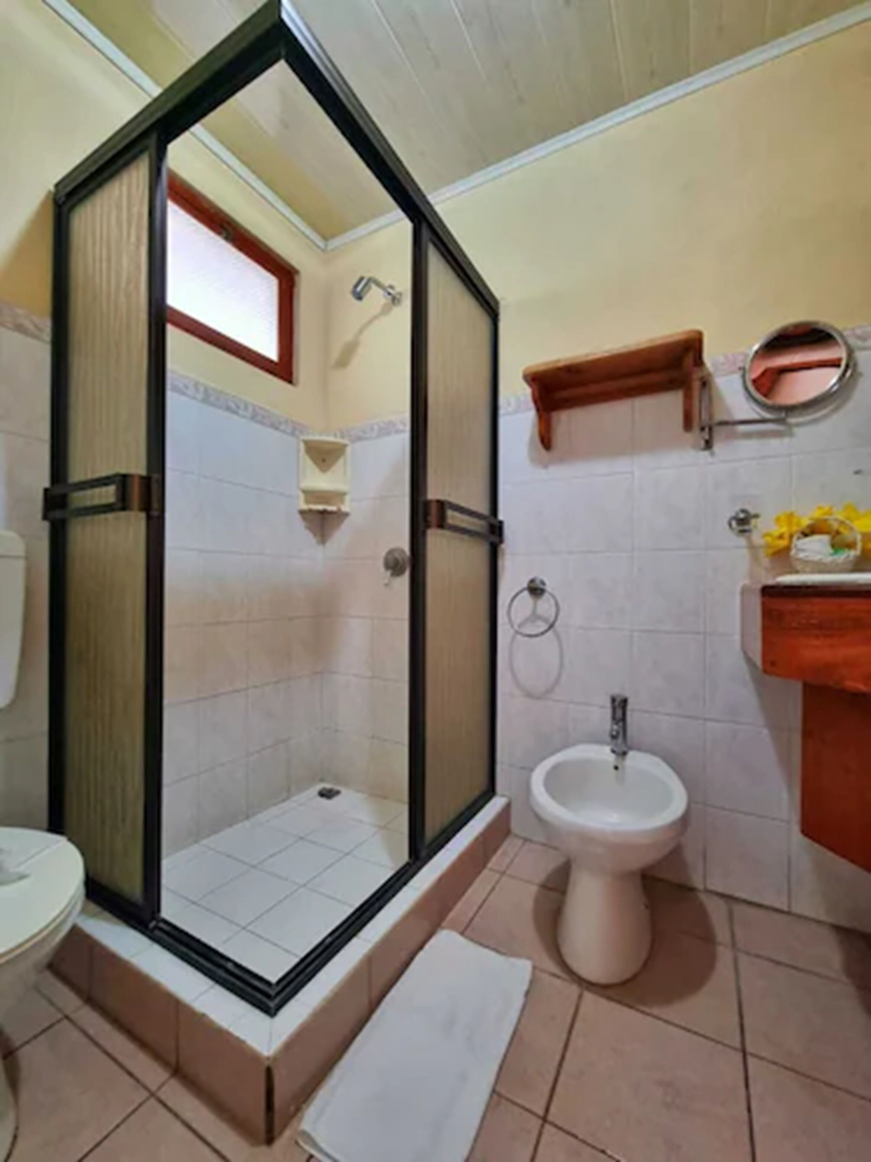 A bathroom with a glass-enclosed shower, a sink, and a toilet.