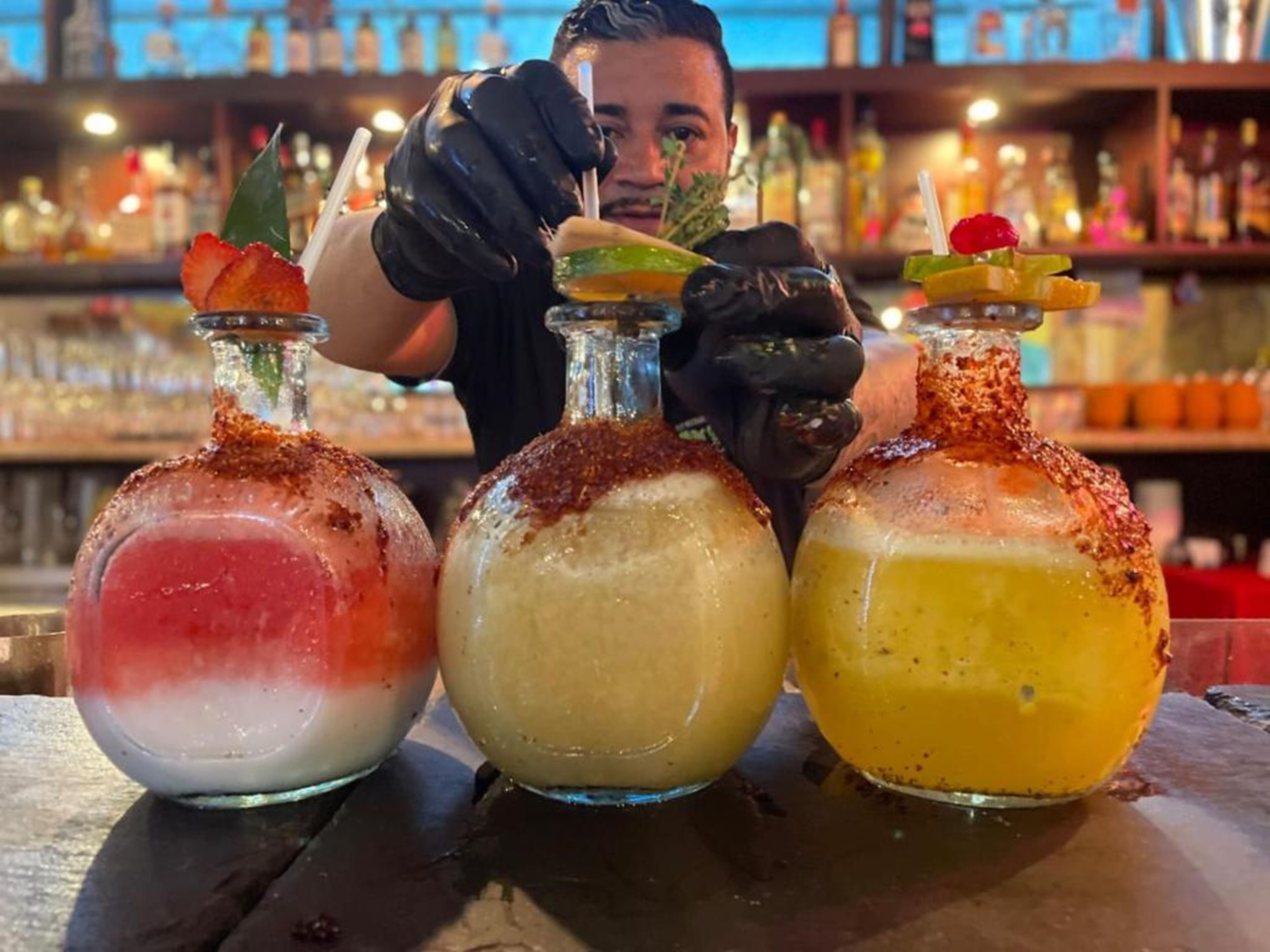 Tre cocktails med pynt på en bardisk.