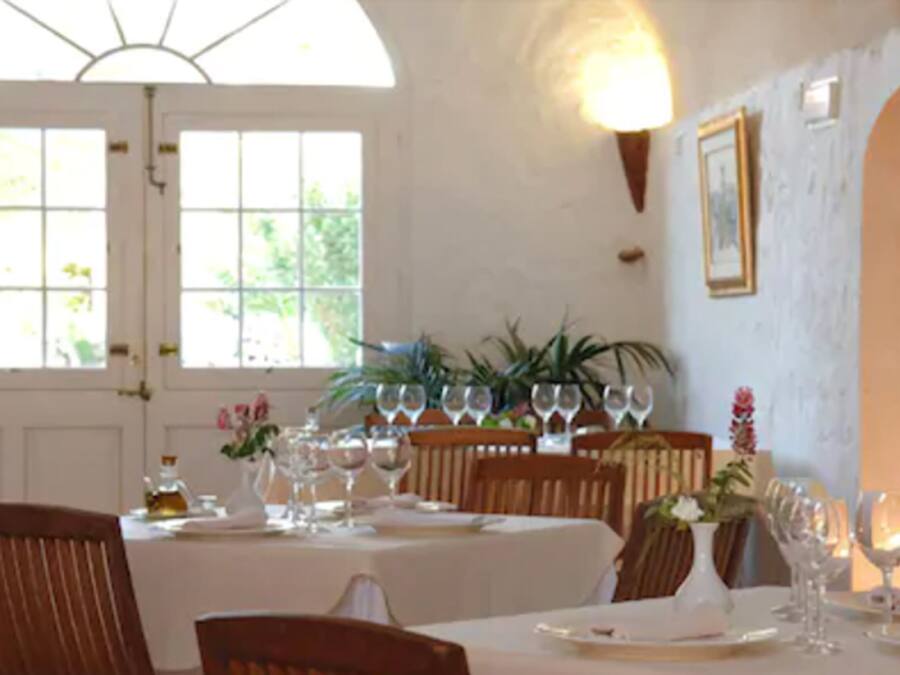 A dining area with a table set for a meal, chairs, and a large window with natural light.