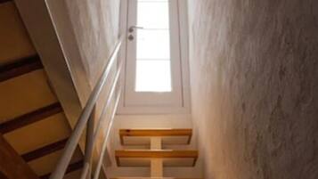 Una escalera estrecha con barandales de madera y una puerta blanca al final.